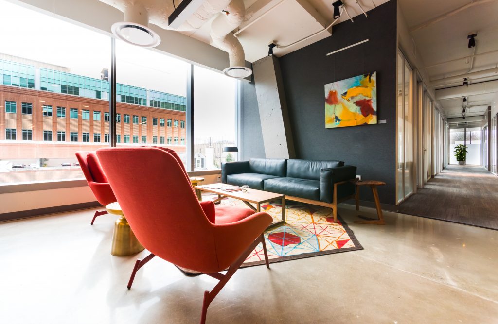 Serendipity Labs lobby with red and black couches and city views.